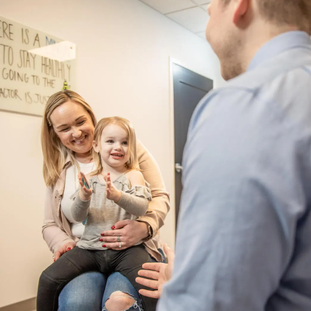 Chiropractor talking with a mother holding her toddler
